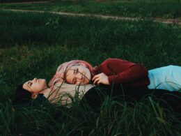 two women lying on green grass