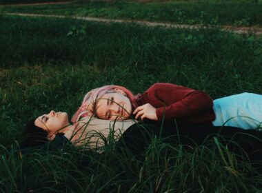 two women lying on green grass