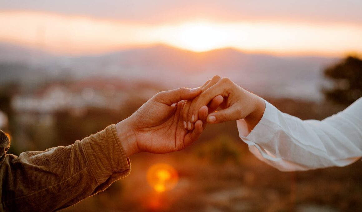 Unrecognizable couple holding hands at sunset