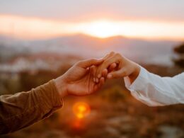 Unrecognizable couple holding hands at sunset