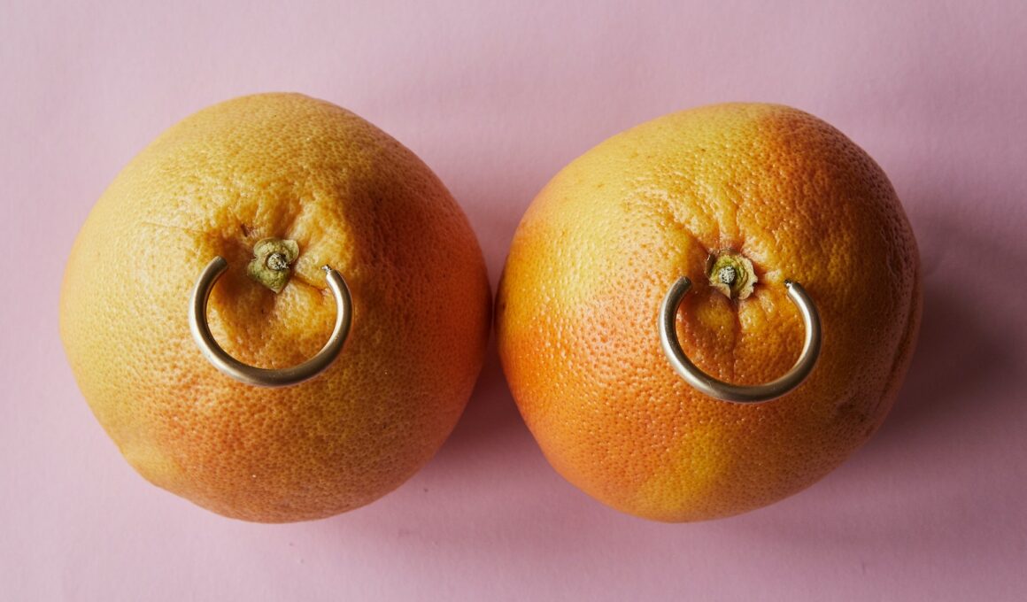 Fresh mandarins with earrings placed on pink surface