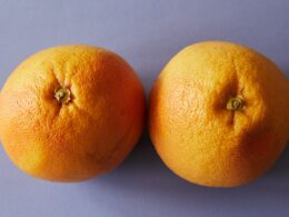 From above pair of ripe juicy oranges placed on light purple background in studio