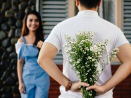 Man Holding Baby's-breath Flower in Front of Woman Standing Near Marble Wall