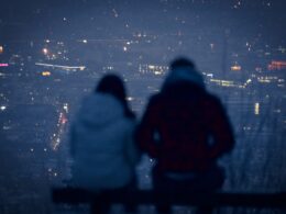 man and woman sitting on bench during night time