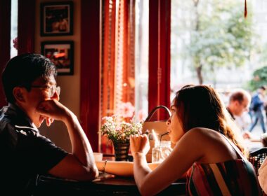 man wearing black collared top sitting on chair in front of table and woman wearing multicolored top