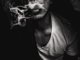 man wearing white V-neck shirt with smoke coming out of mouth