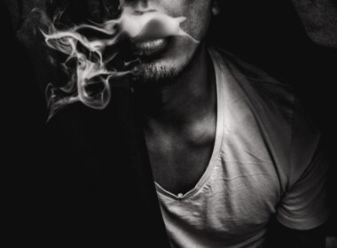 man wearing white V-neck shirt with smoke coming out of mouth