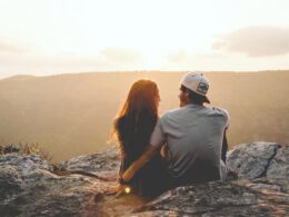 man and woman sitting on rock during daytime