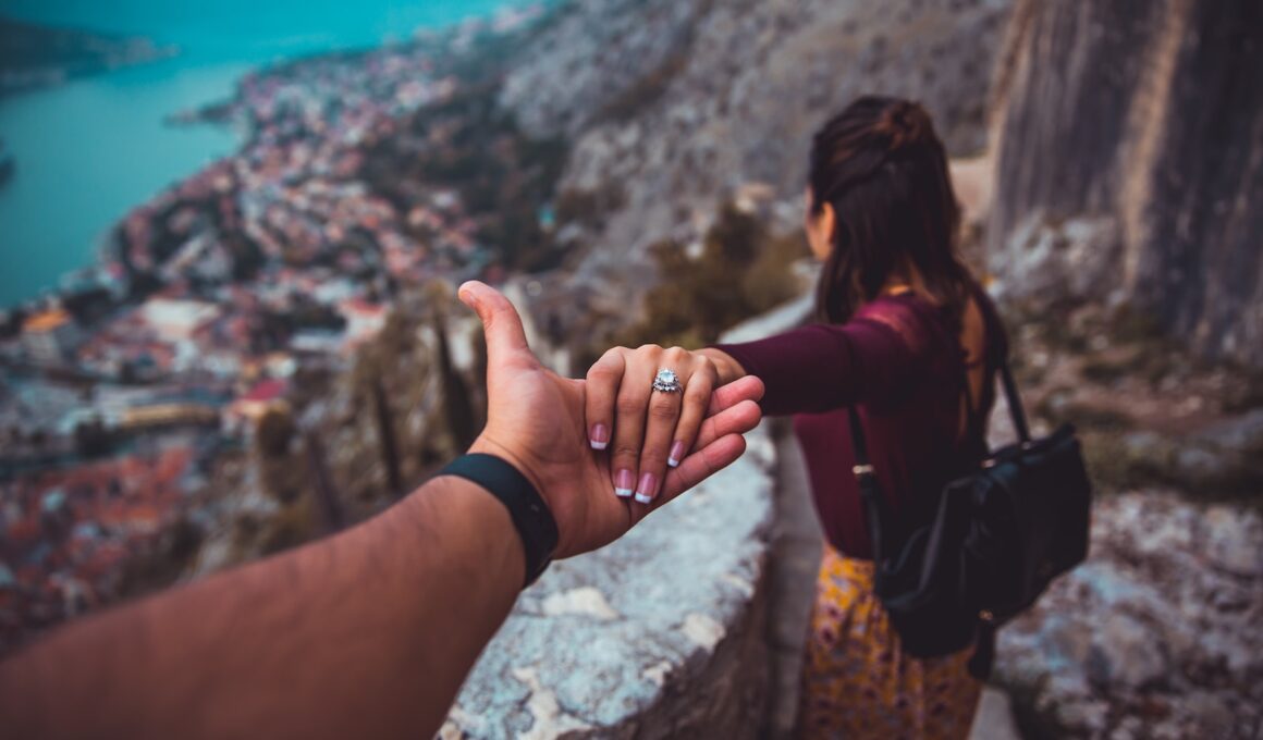 woman holding man's hand while looking on scenery of building beside body of water during daytime