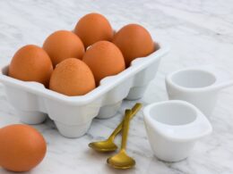 tray of brown eggs beside two spoons